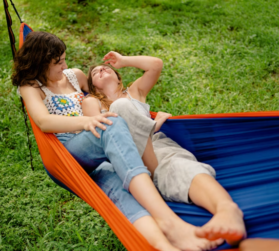 A couple laying in a hammock in a meadow
