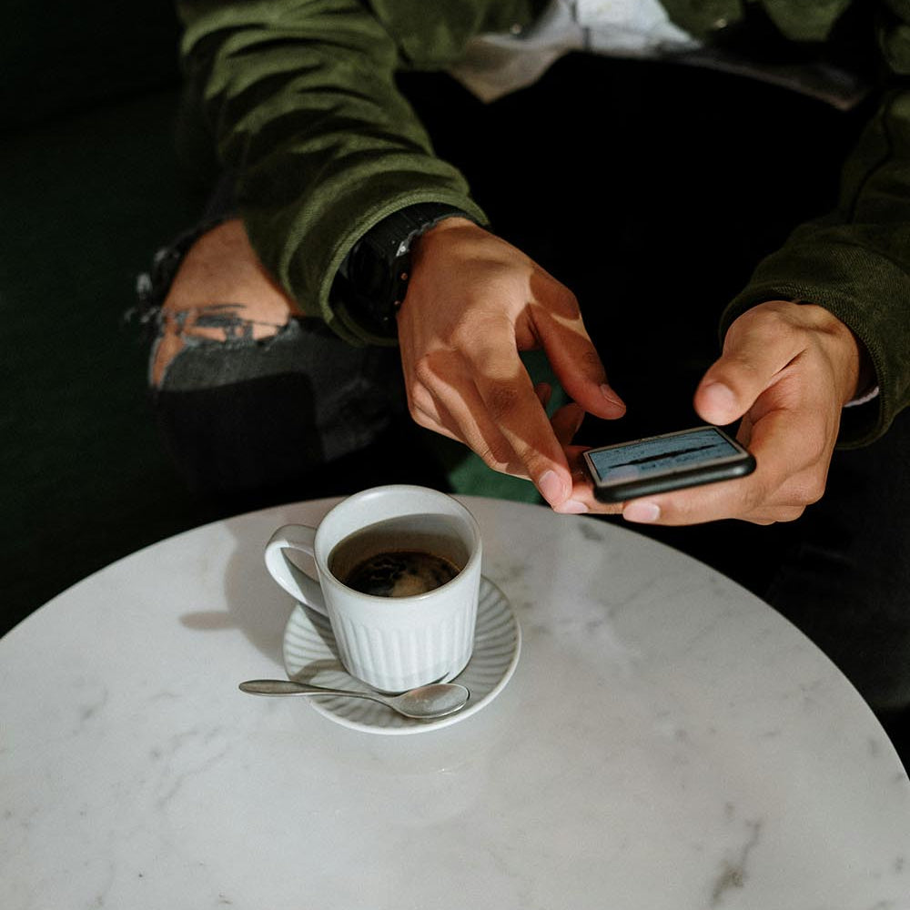 Man holding an iphone with a coffee