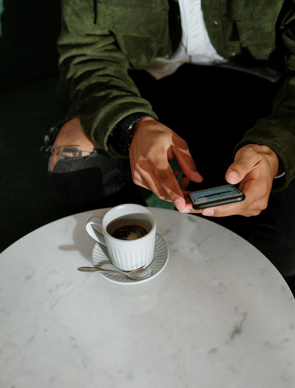 Man holding an iphone with a coffee